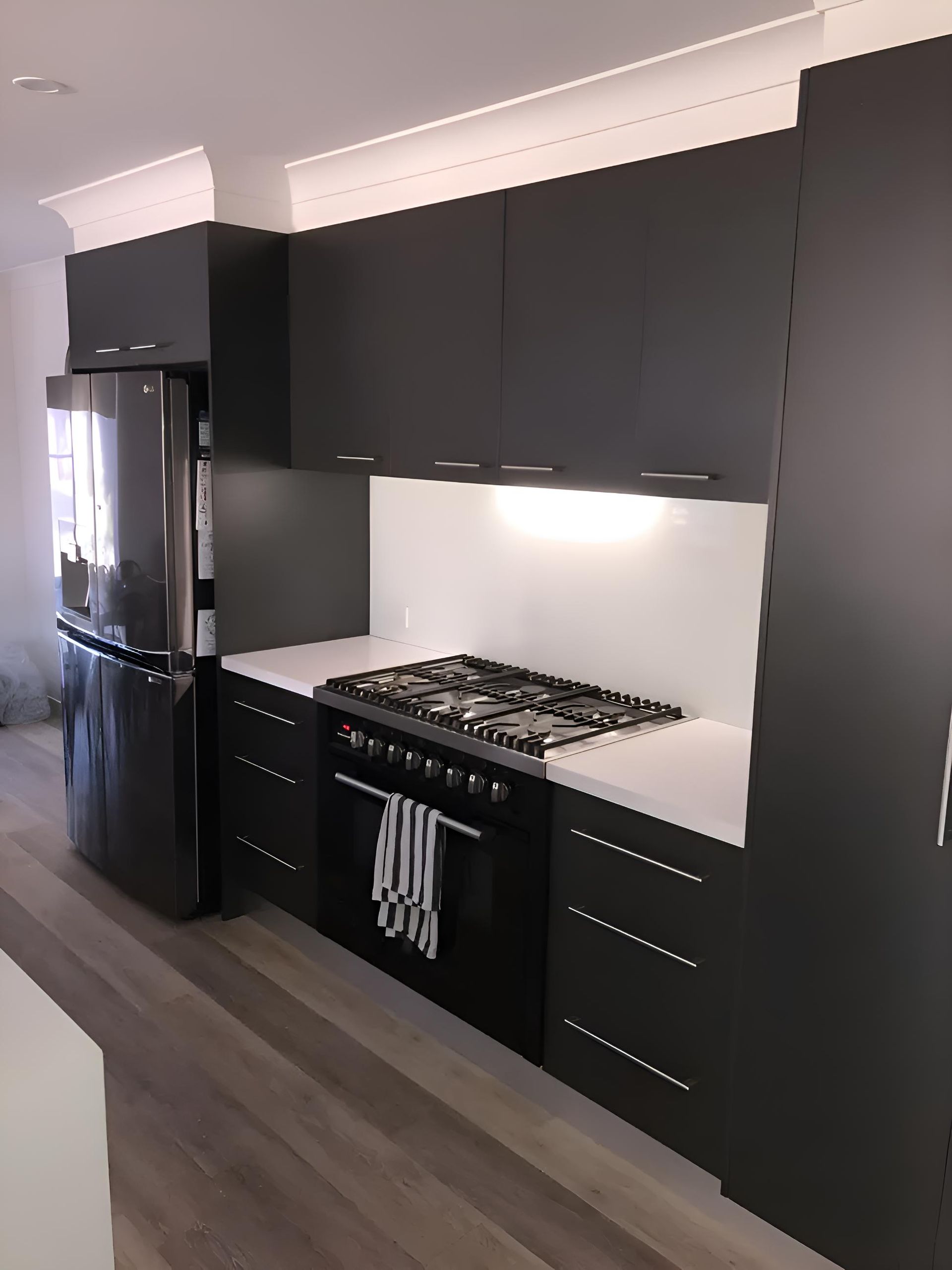 A Kitchen With Black Cabinets and a Stove Top Oven — Hey Presto Kitchens & Renovations in Armidale, NSW