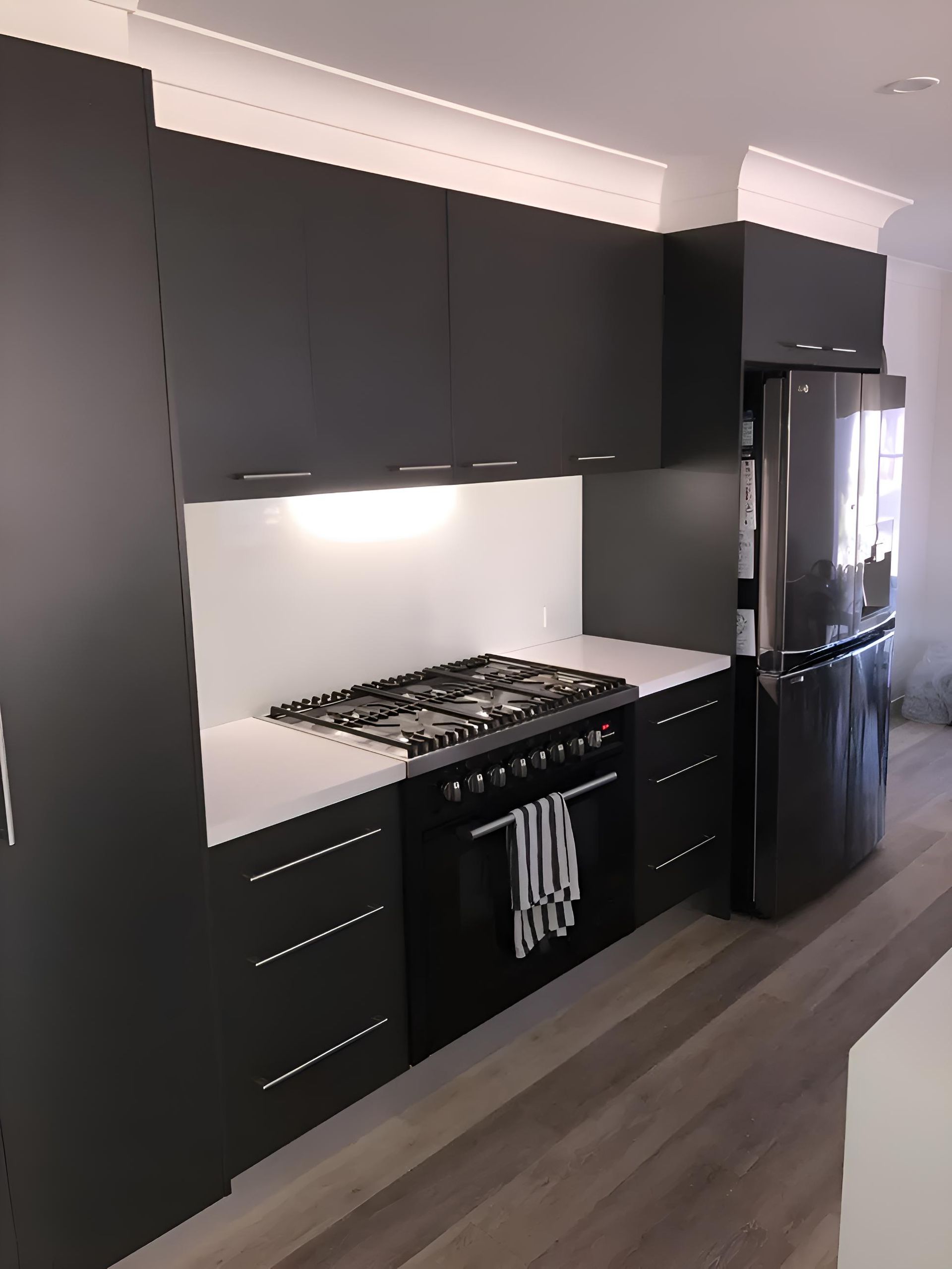 A Kitchen With Black Cabinets And A Black Refrigerator — Hey Presto Kitchens & Renovations in Guyra, NSW
