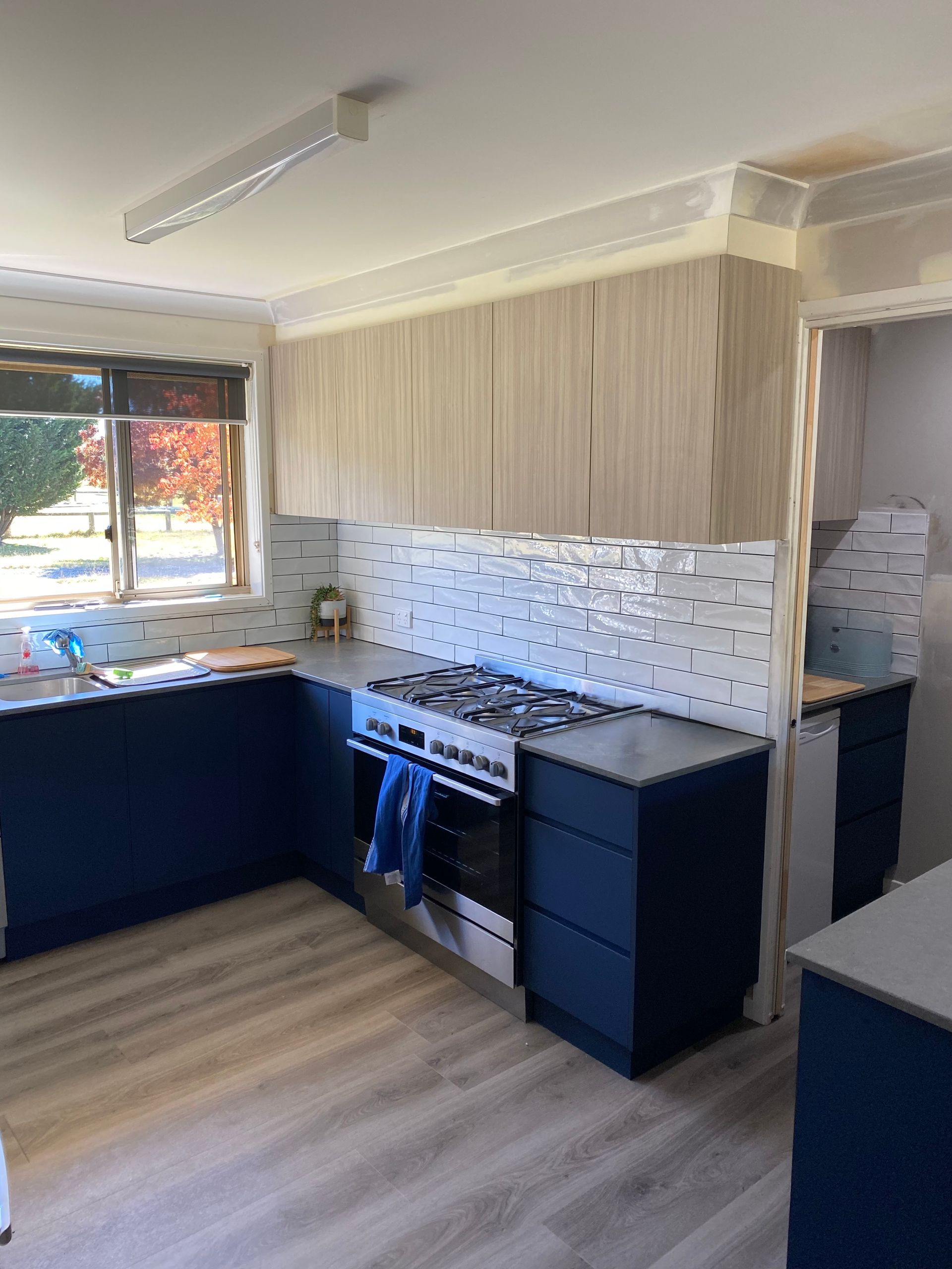 A Kitchen With Blue Cabinets, a Stove, and a Window — Hey Presto Kitchens & Renovations in Armidale, NSW