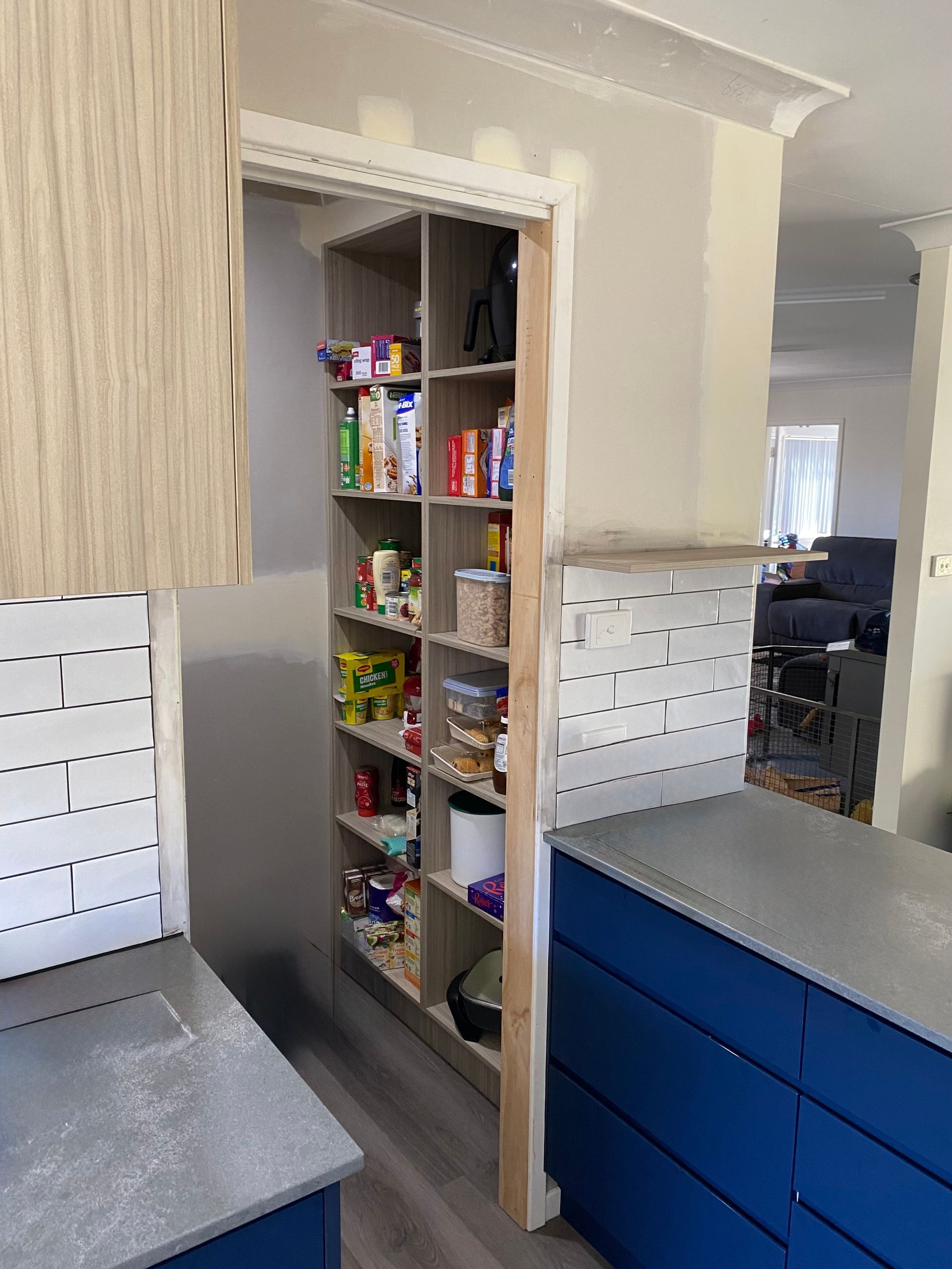 A Kitchen With Blue Cabinets and a Pantry Filled With Food — Hey Presto Kitchens & Renovations in Armidale, NSW