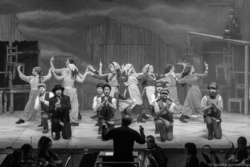 A black and white photo of a group of people dancing on a stage.