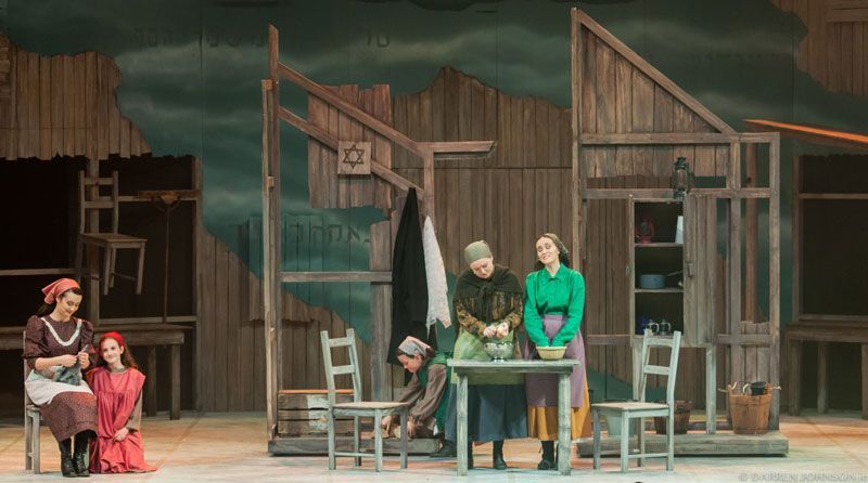 A group of people are standing around a table on a stage.