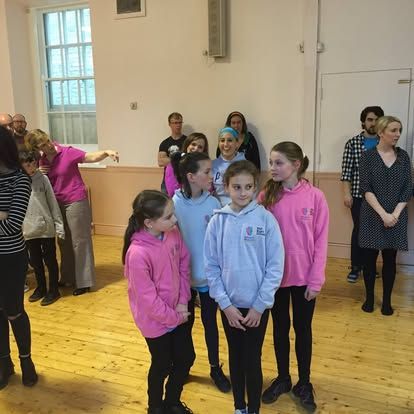 A group of people standing in a room wearing pink hoodies