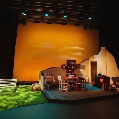 A stage set for a play with a table and chairs on it.