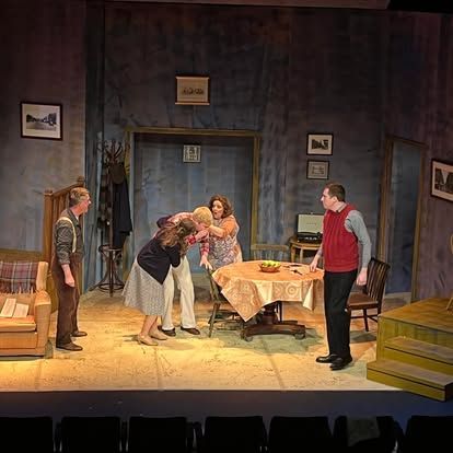 A group of people are standing around a table on a stage.