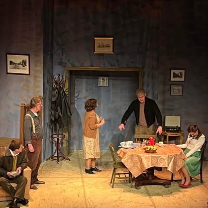 A group of people are standing around a table on a stage.
