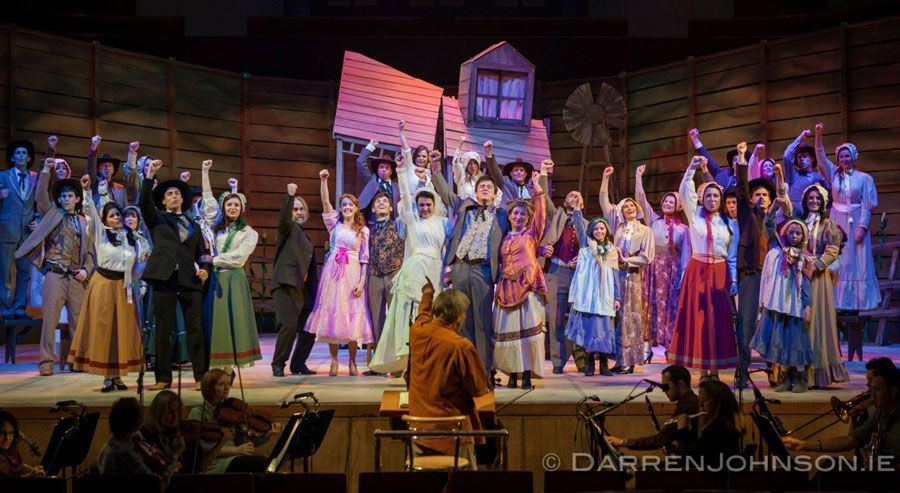 A large group of people are standing on a stage with their hands in the air.