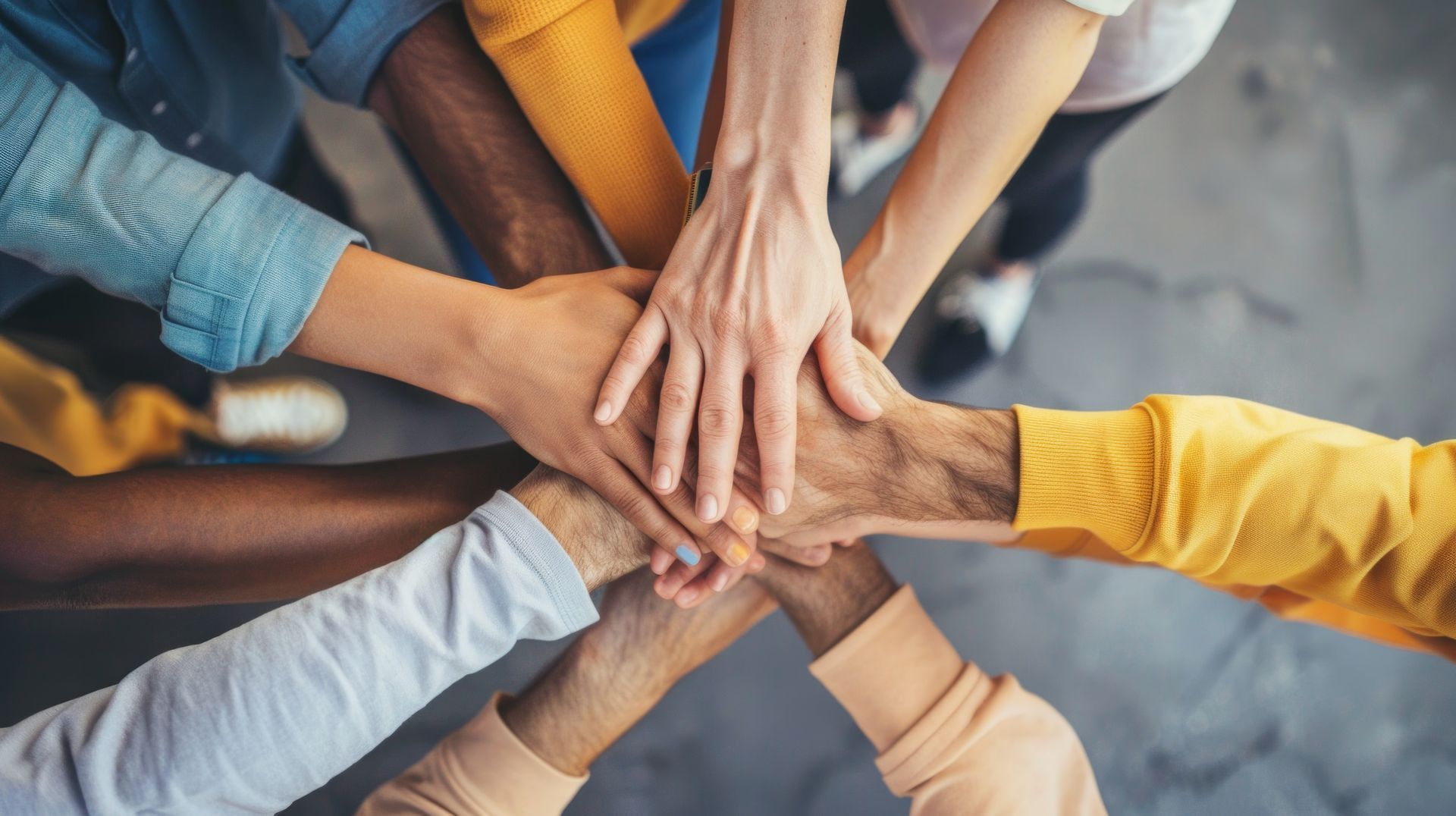 A group of people are putting their hands together in a circle.