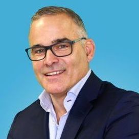 A man wearing glasses and a suit is smiling for the camera.