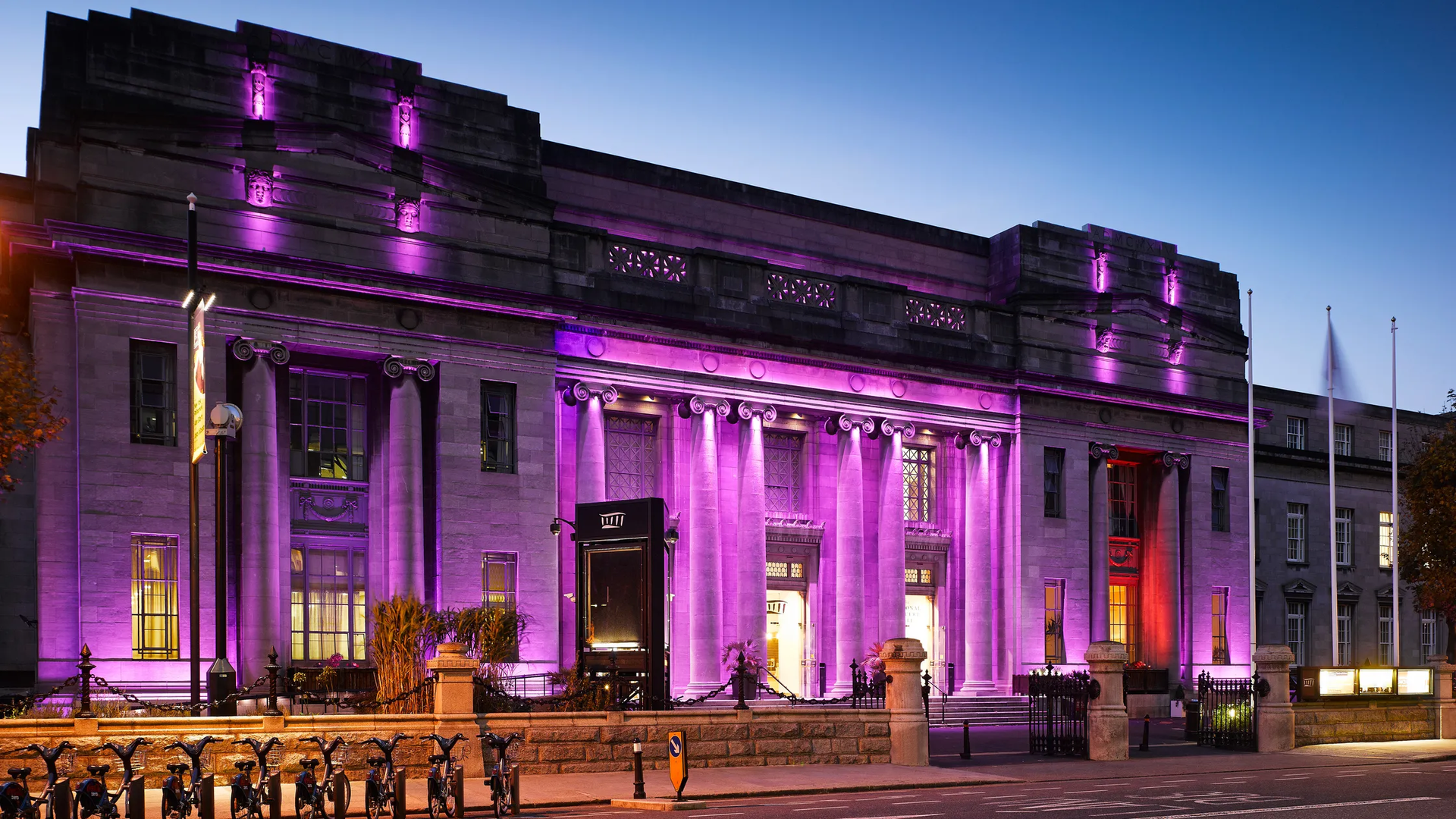 A large building is lit up with purple lights at night.