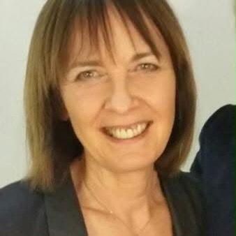 A woman is smiling for the camera and wearing a black jacket.