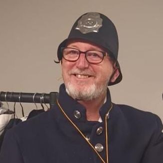 A man with a beard is wearing a police hat and glasses.