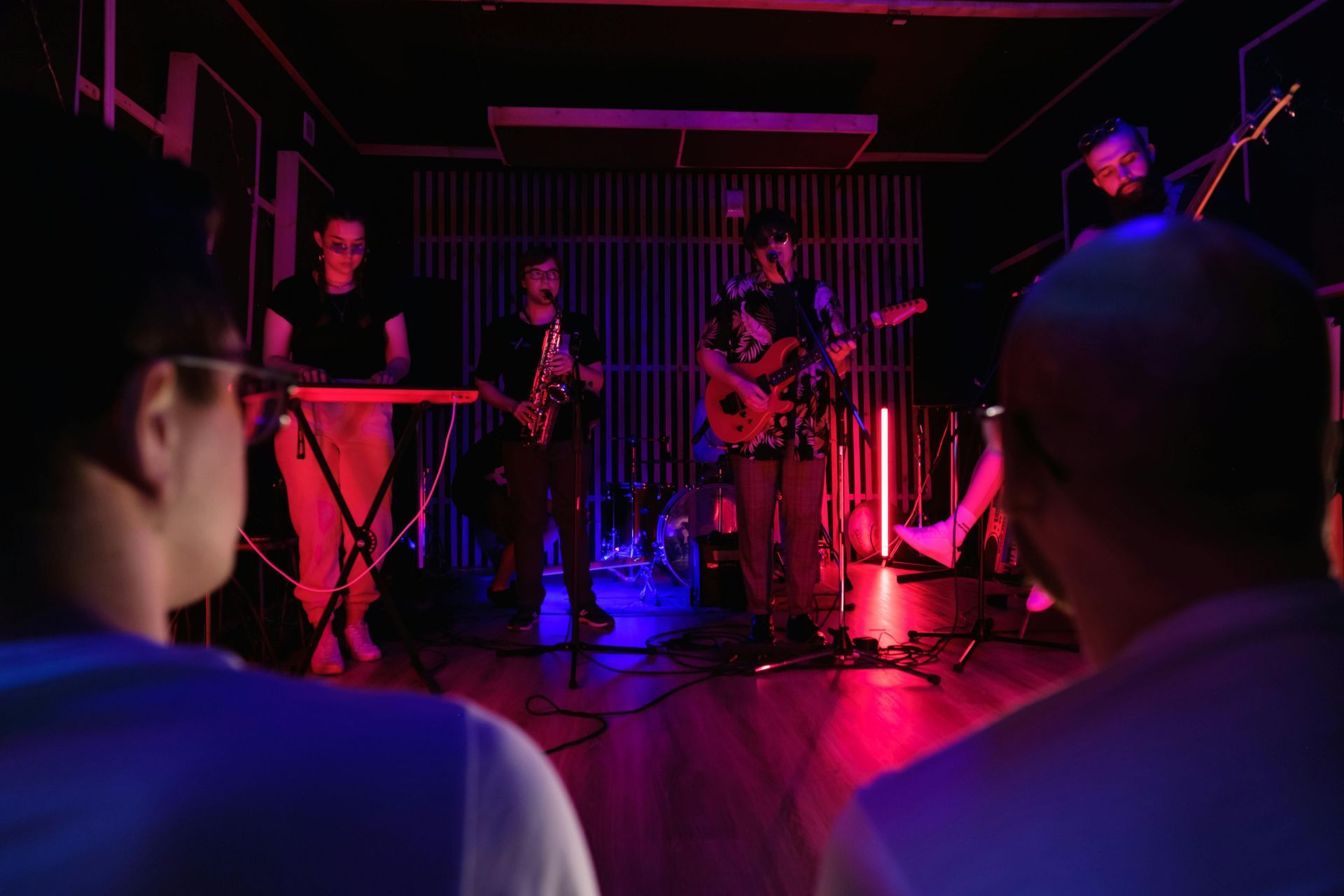 A group of people are sitting in a dark room watching a band perform on stage.