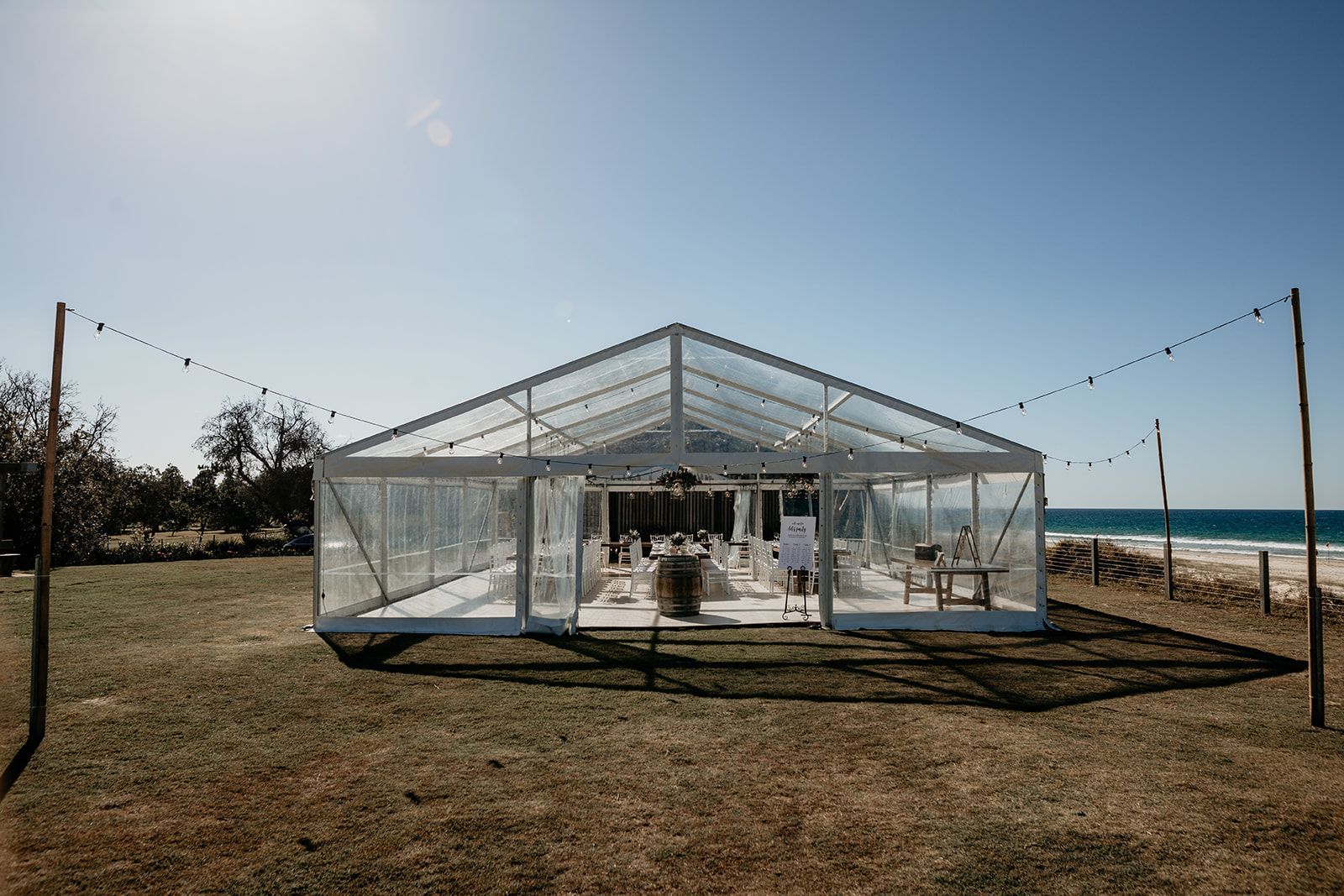 A Clear Tent Is Sitting In The Middle Of A Field Next To The Ocean — Wedding & Event Hire In Byron Bay, NSW
