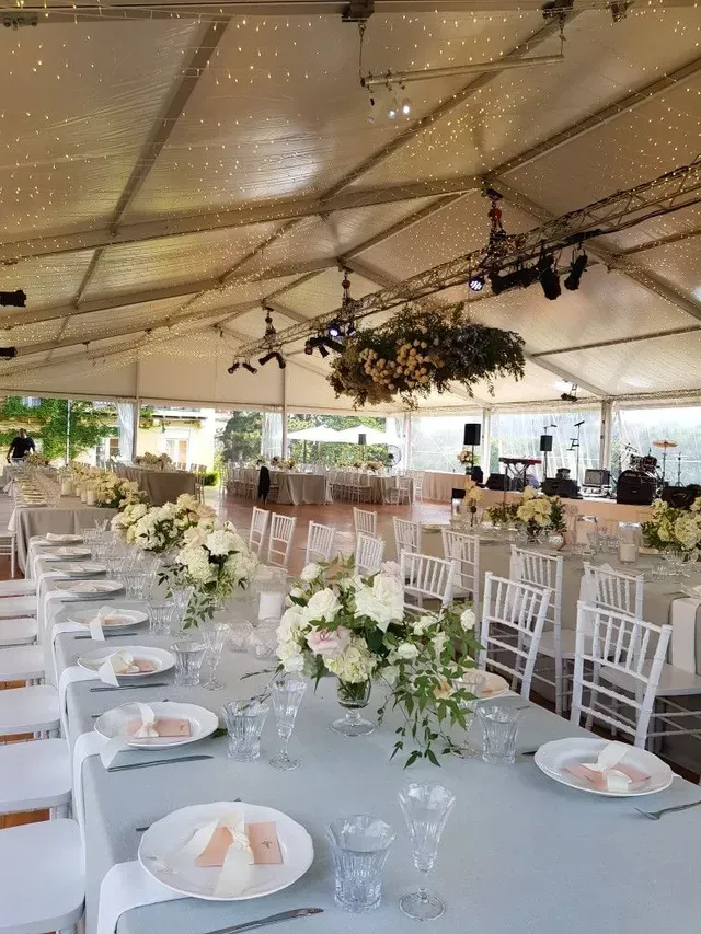 A large tent with tables and chairs set up for a wedding reception.