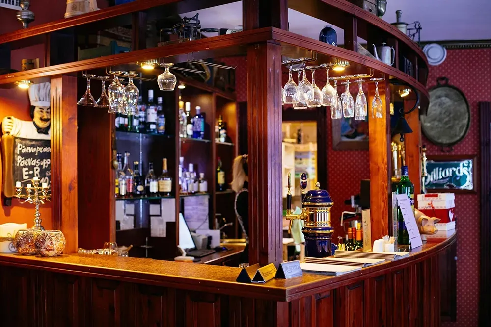 Wood-paneled bar with hanging wine glasses, bottles, and a polished counter in a cozy pub interior