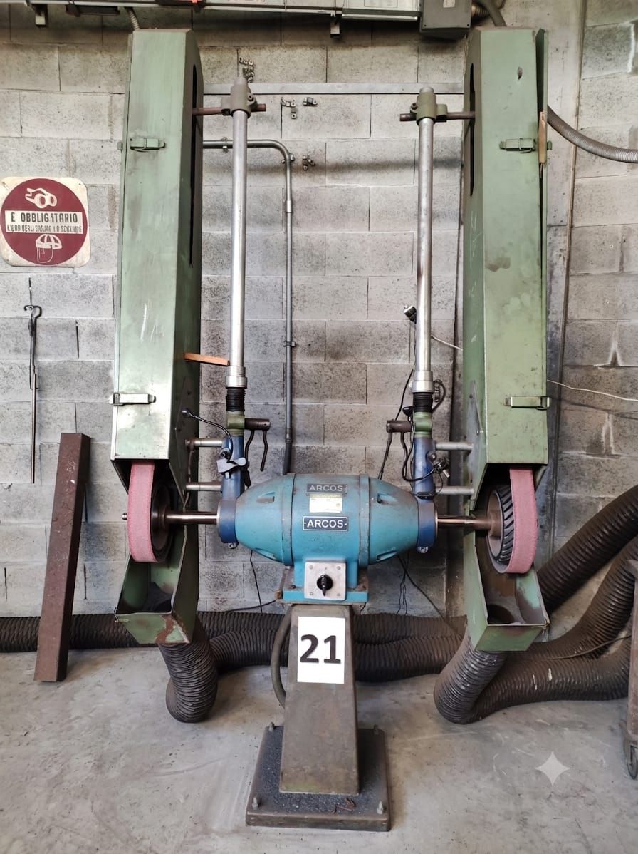 Macchina industriale con motore e tubi blu montati tra supporti verdi in un'officina, etichettata 21