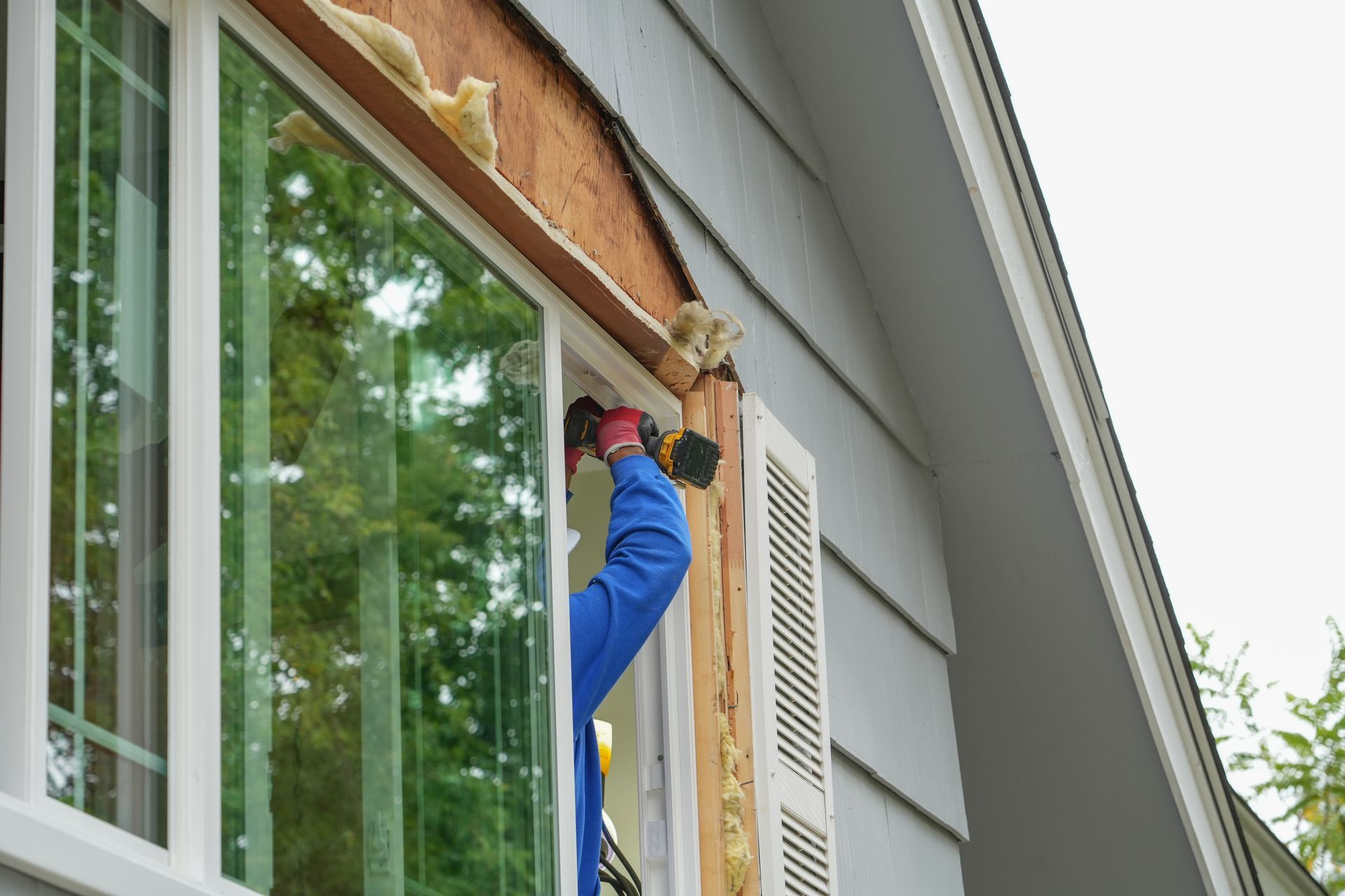 Worker installing a new window in home siding.