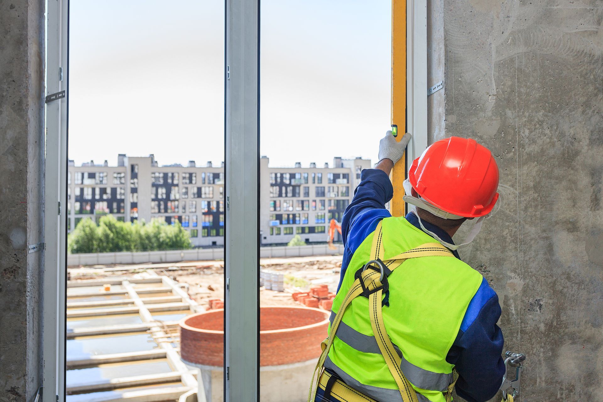 A worker in an orange helmet installs a double-glazed window in a new house. A worker in an orange helmet installs a double-glazed window in a new house.