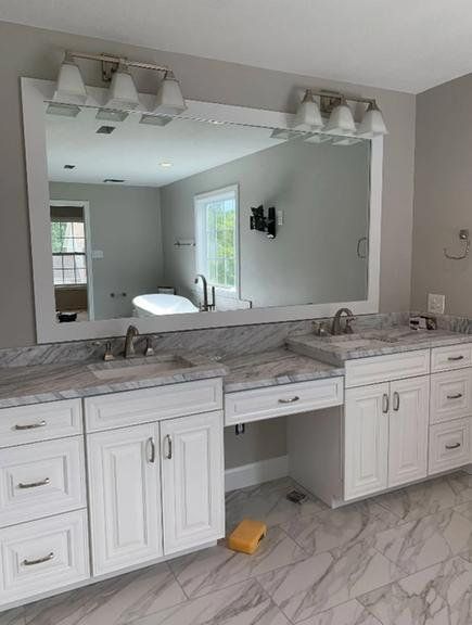 Double white vanity with marble countertop, large mirror, and two lighting fixtures in a bathroom with tiled flooring.