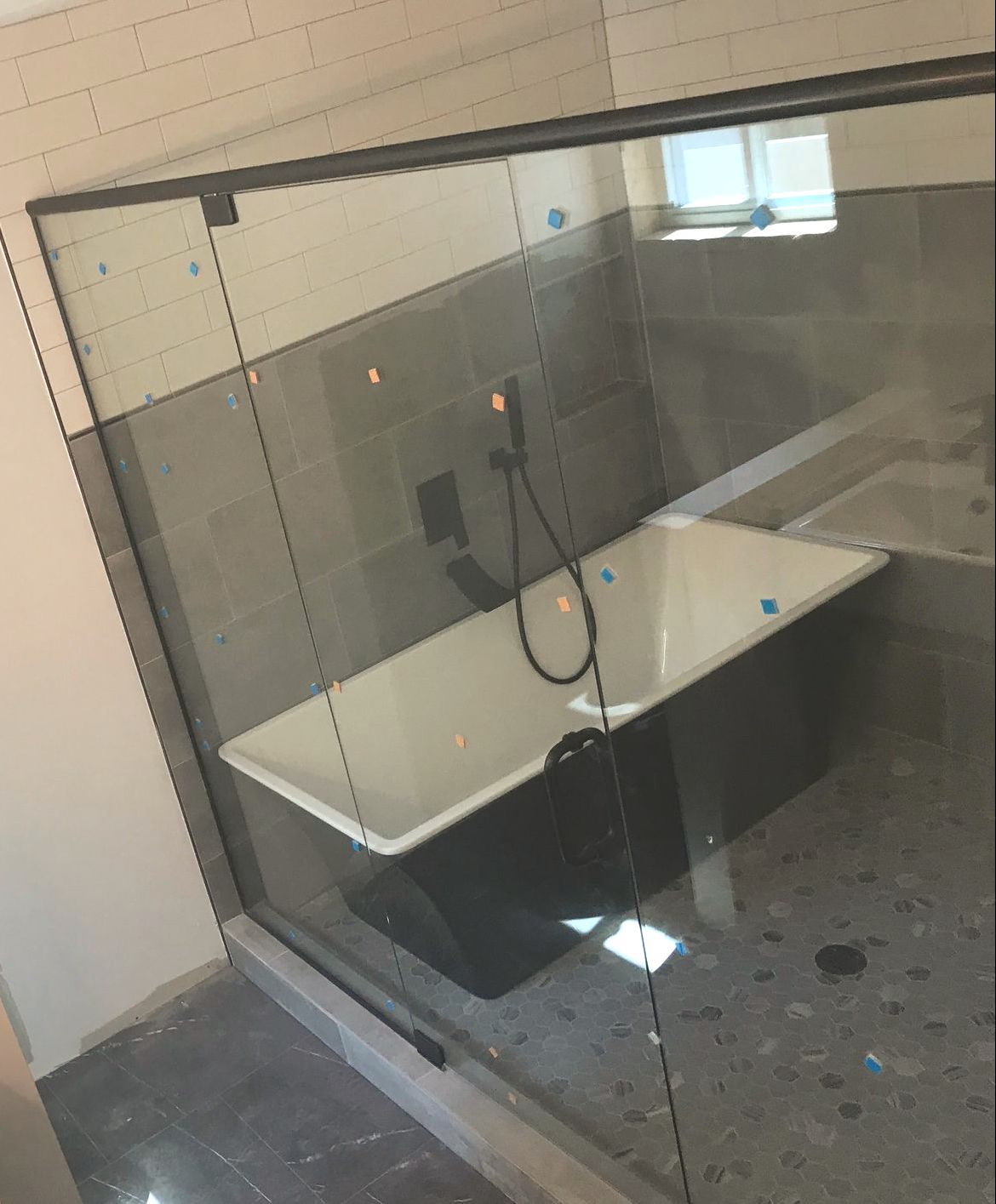 A modern bathroom with a freestanding white tub, dark grey tiled walls, and a glass-enclosed shower area.