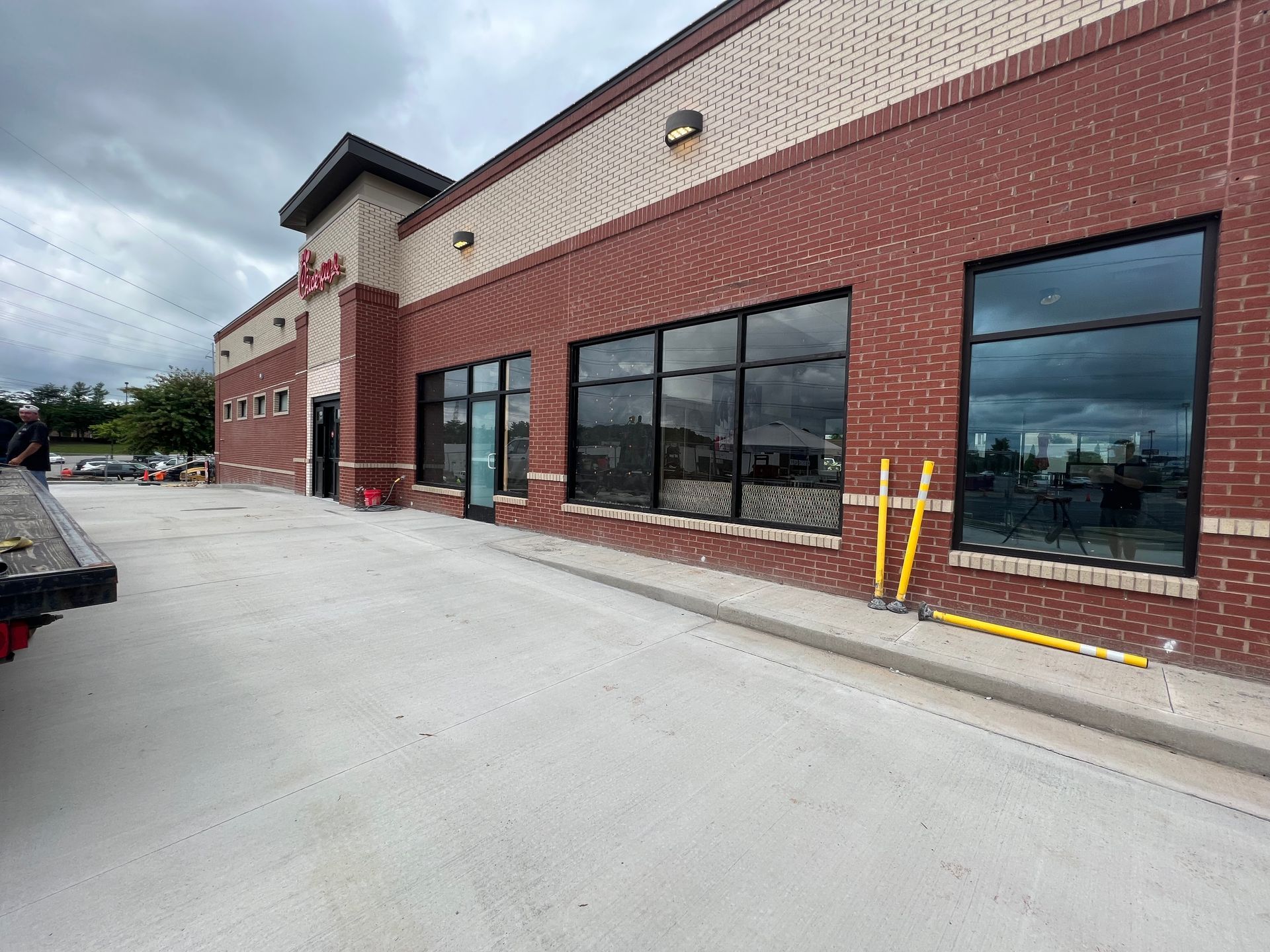 Exterior view of a brick commercial building with large glass windows under a cloudy sky.