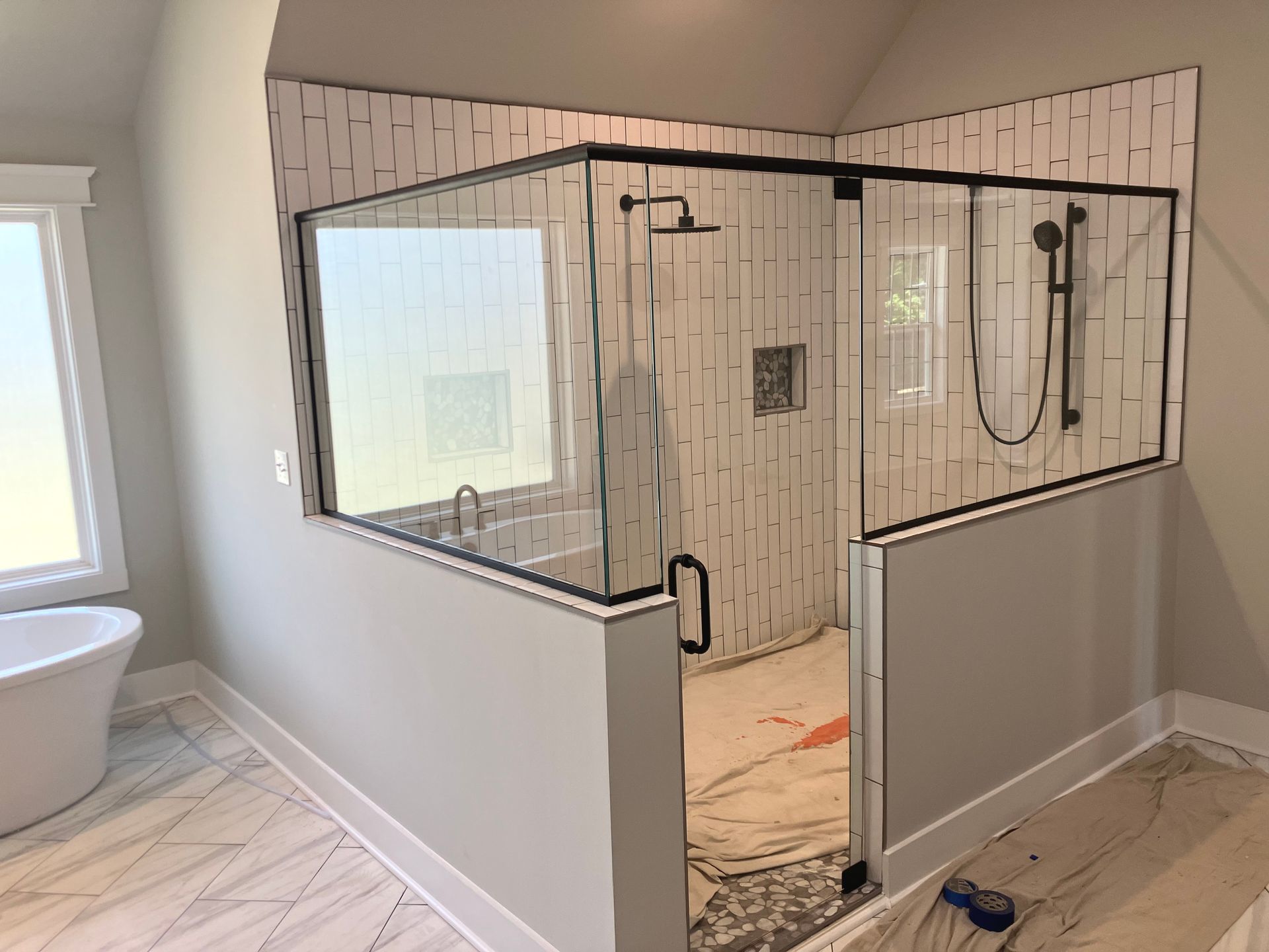 A modern bathroom featuring a walk-in shower with white vertical tiles, black hardware, and a glass enclosure.