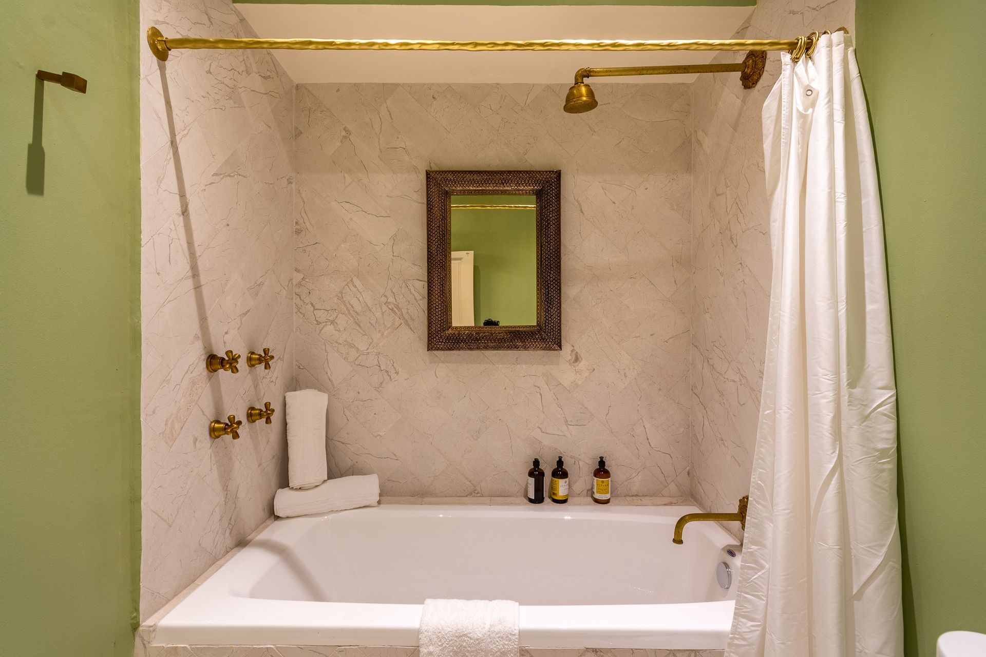 Hay una bañera en el baño con cortina de ducha y espejo.