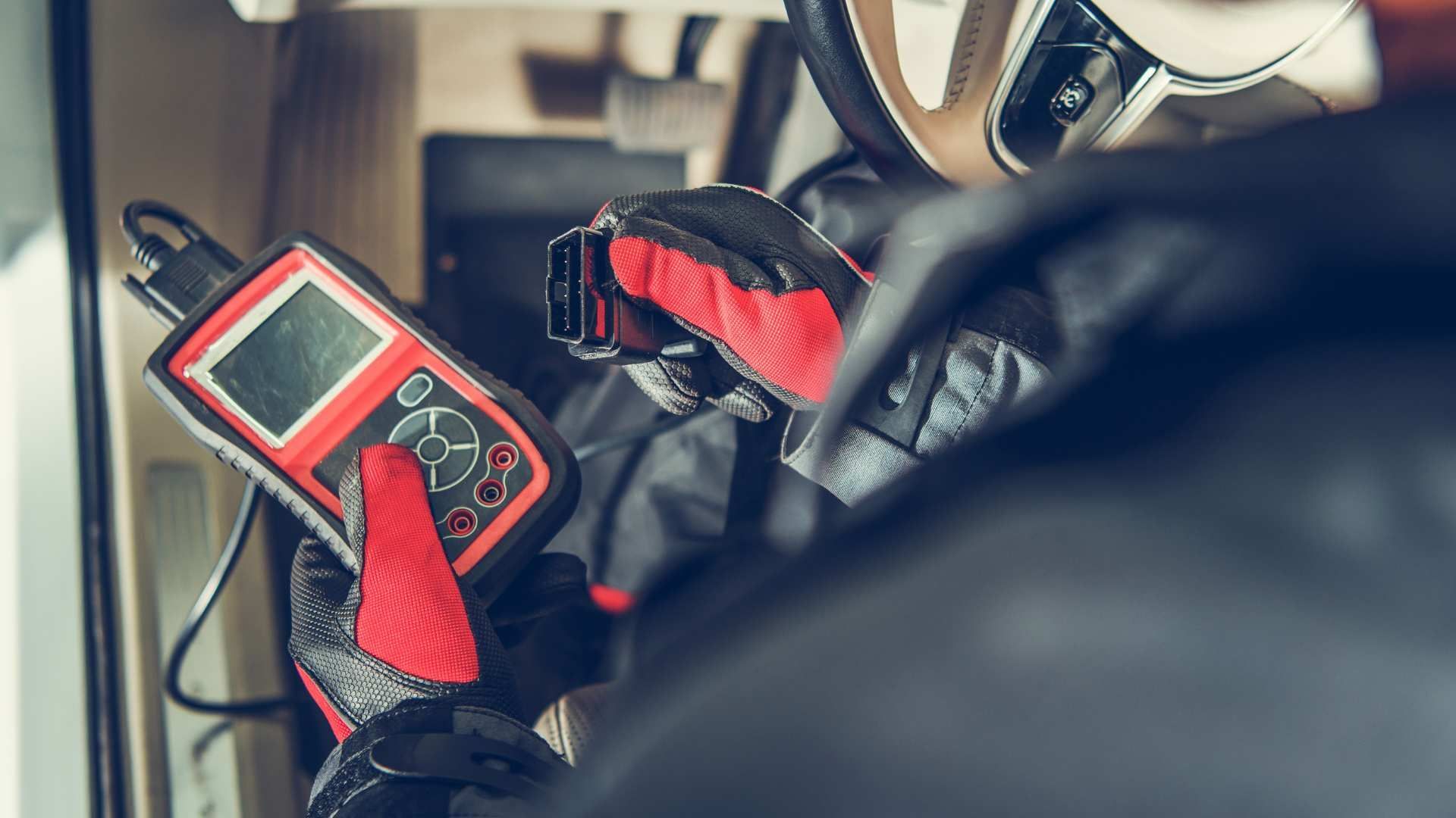 Handheld device with red case strapped inside a vehicle, near steering wheel and seatbelt