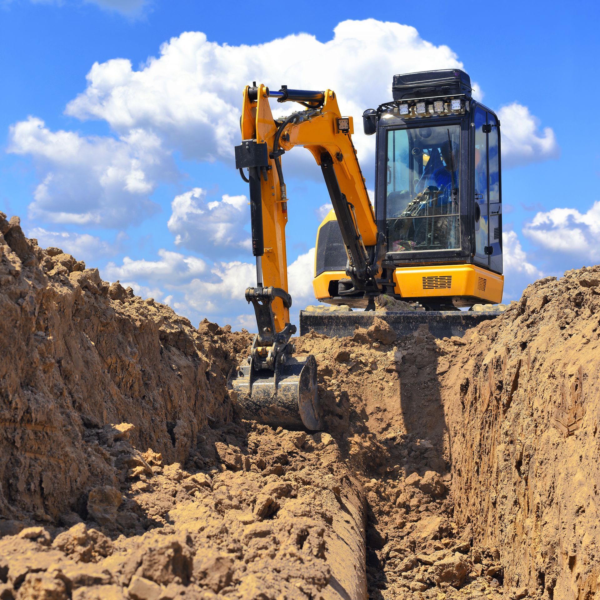 A yellow excavator is digging a hole in the dirt