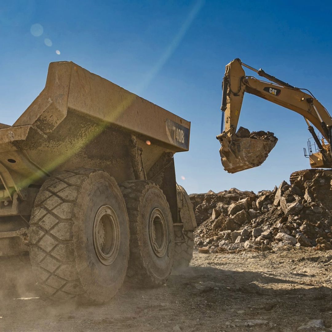A dump truck is being loaded with rocks by an excavator