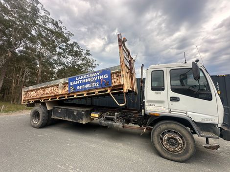 White and brown flatbed truck with rust. Sign for