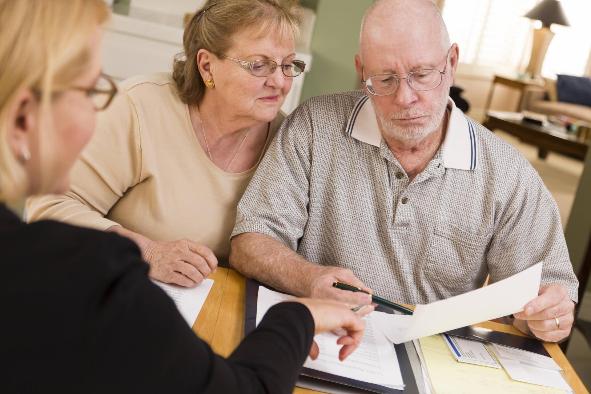 A man and a woman are sitting at a table looking at a piece of paper.