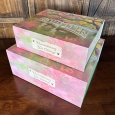 Two decorative keepsake boxes, one atop the other, with a painting of a bridge, and text that reads
