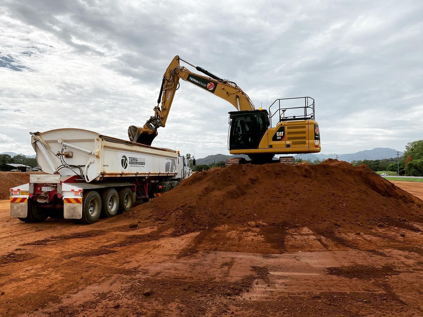 Yellow Excavator Loading a White Dump Truck — Terranovus Earthworks & Plant Hire in Cairns City, QLD