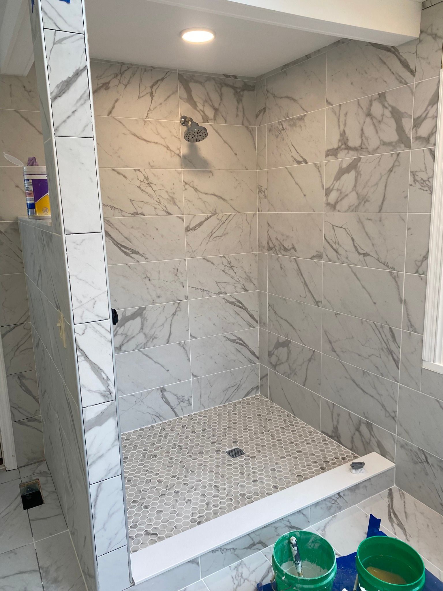 A bathroom with marble tiles and a walk in shower.