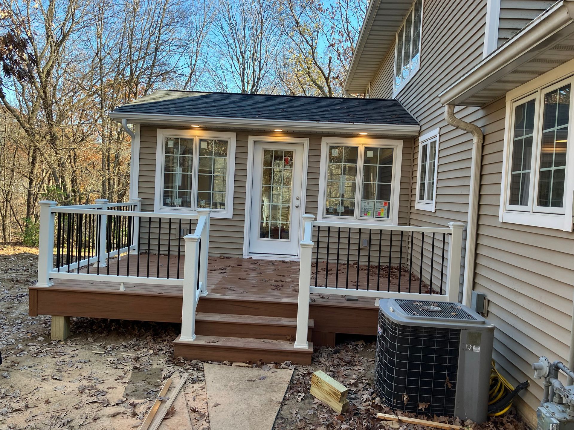 A large house with a deck and a air conditioner in front of it.