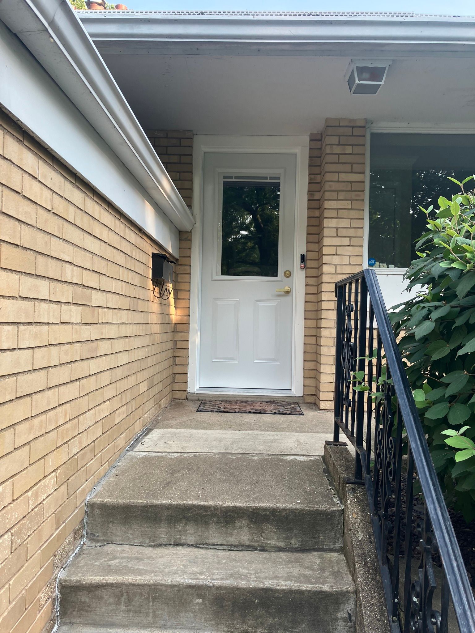 A brick house with a white door and stairs leading to it.
