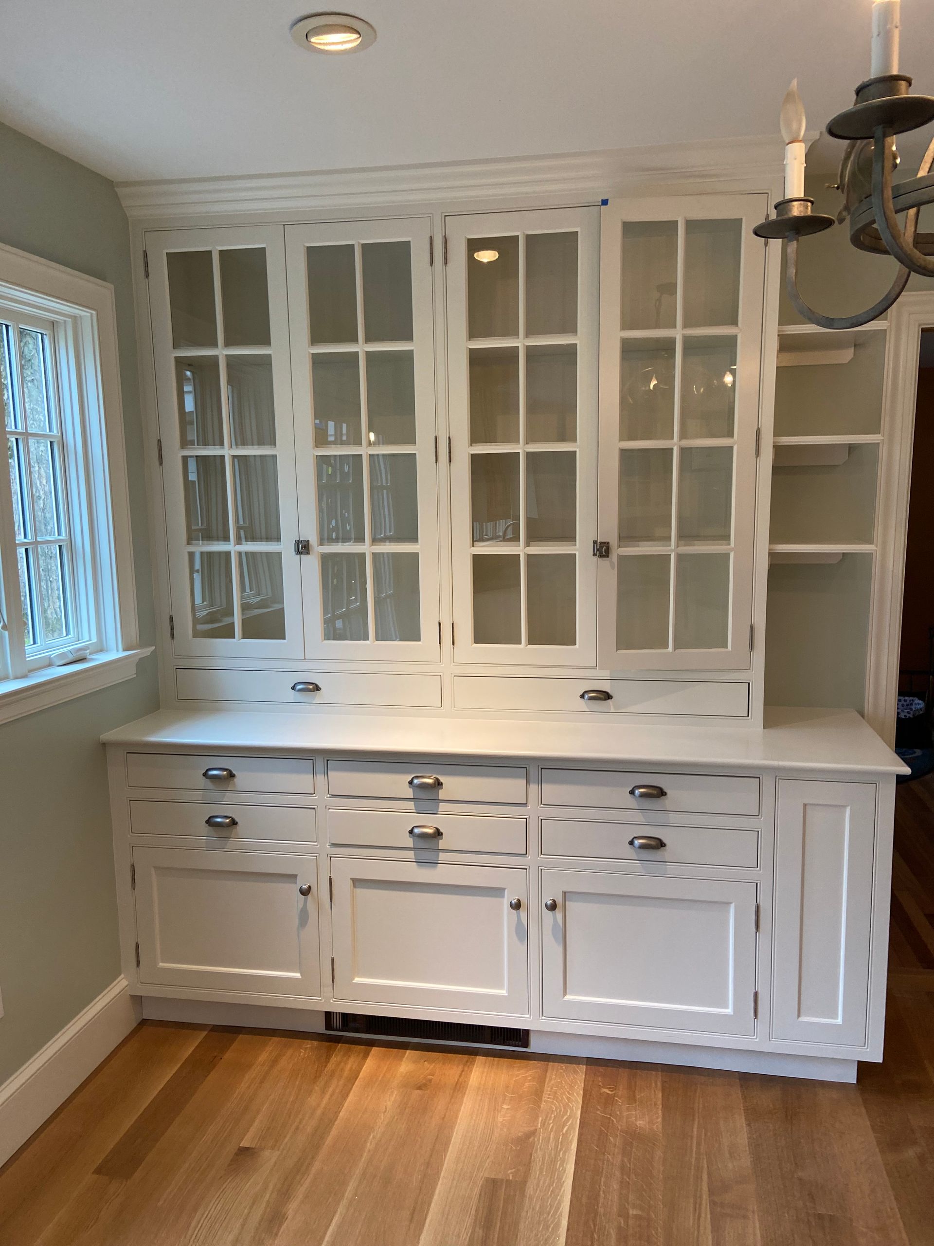 A kitchen with white cabinets and glass doors