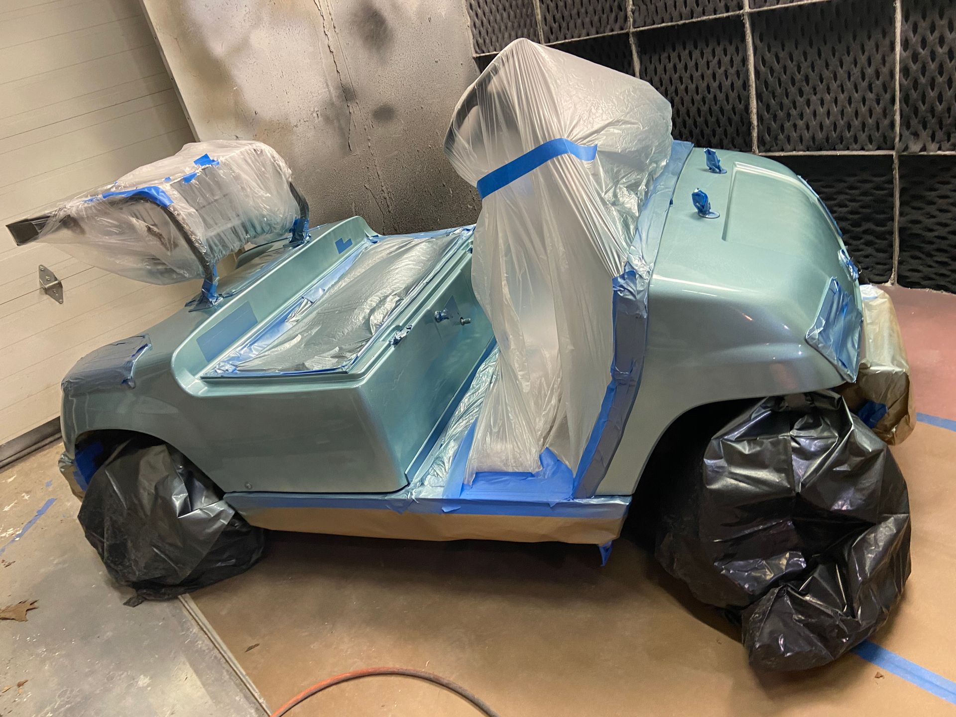 A golf cart is being painted in a paint booth.