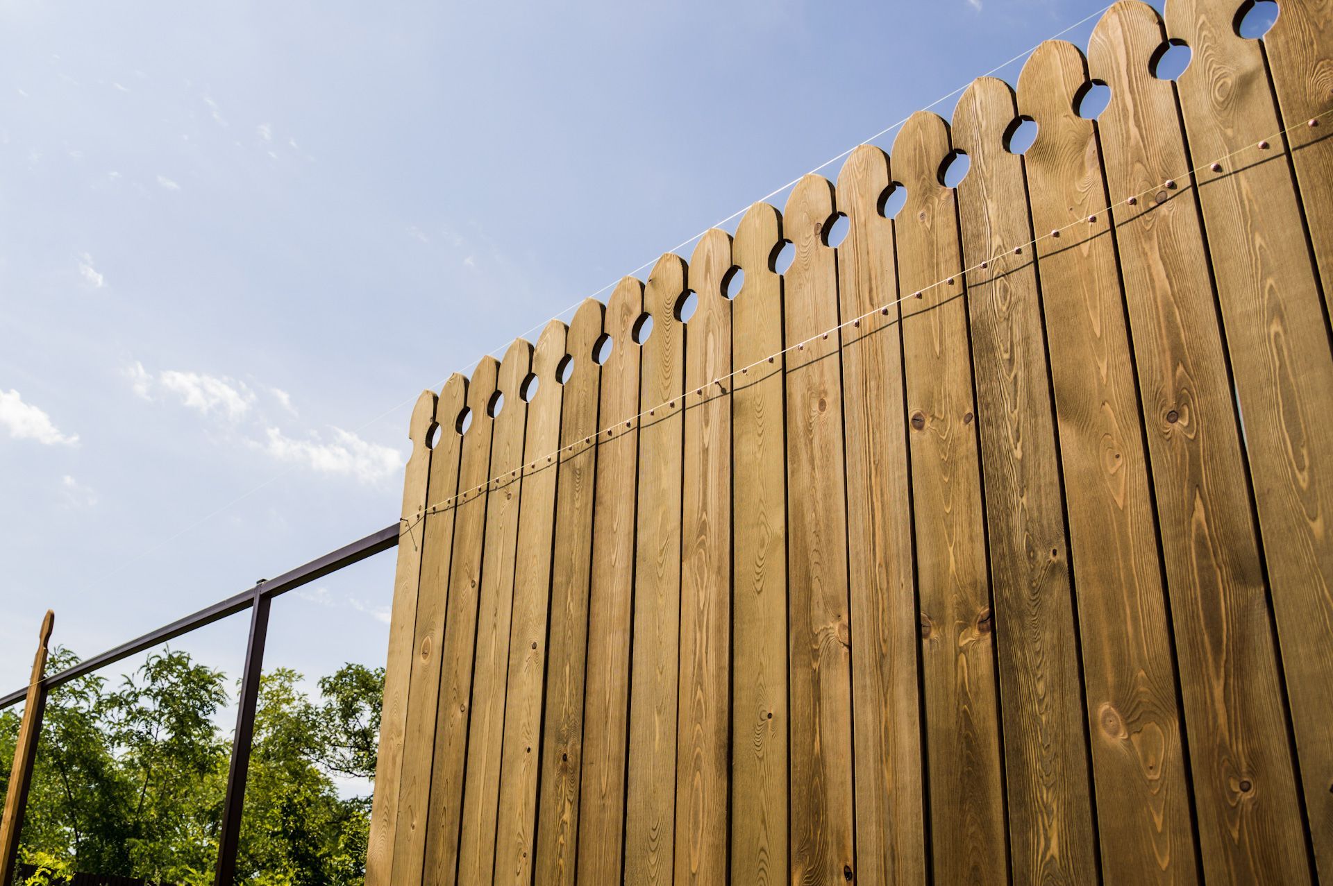 A close up of a wooden fence with a blue sky in the background.