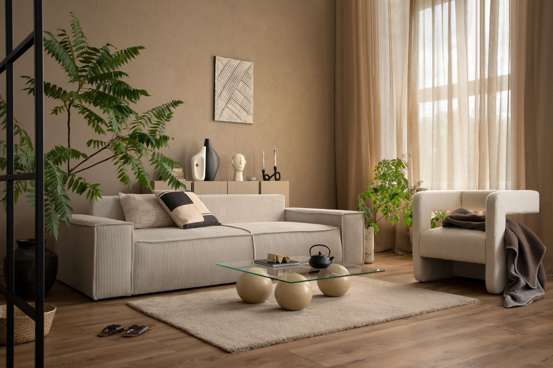 A living room with a couch , chair , coffee tables and plants.