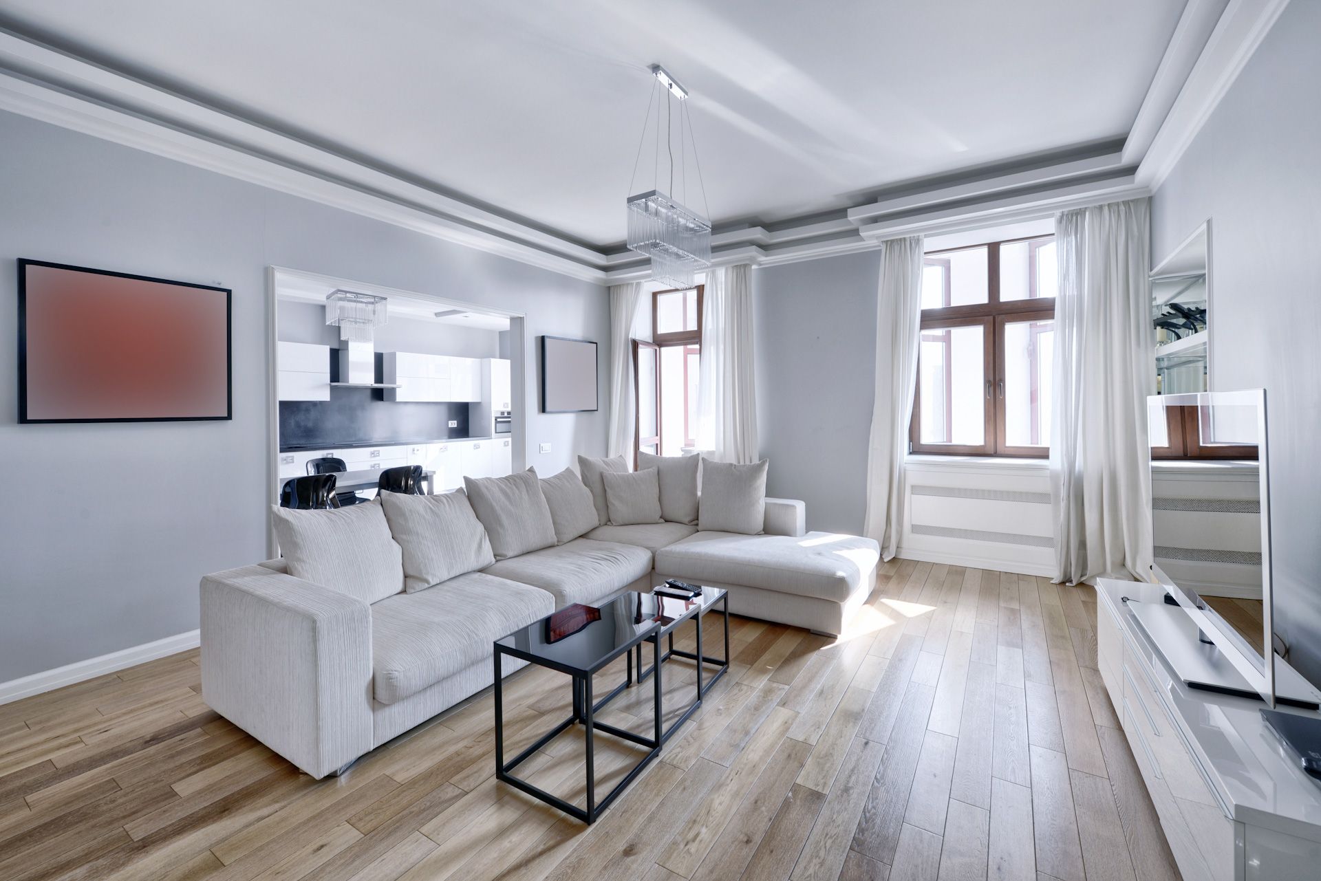 A living room with a white sectional couch and a flat screen tv.
