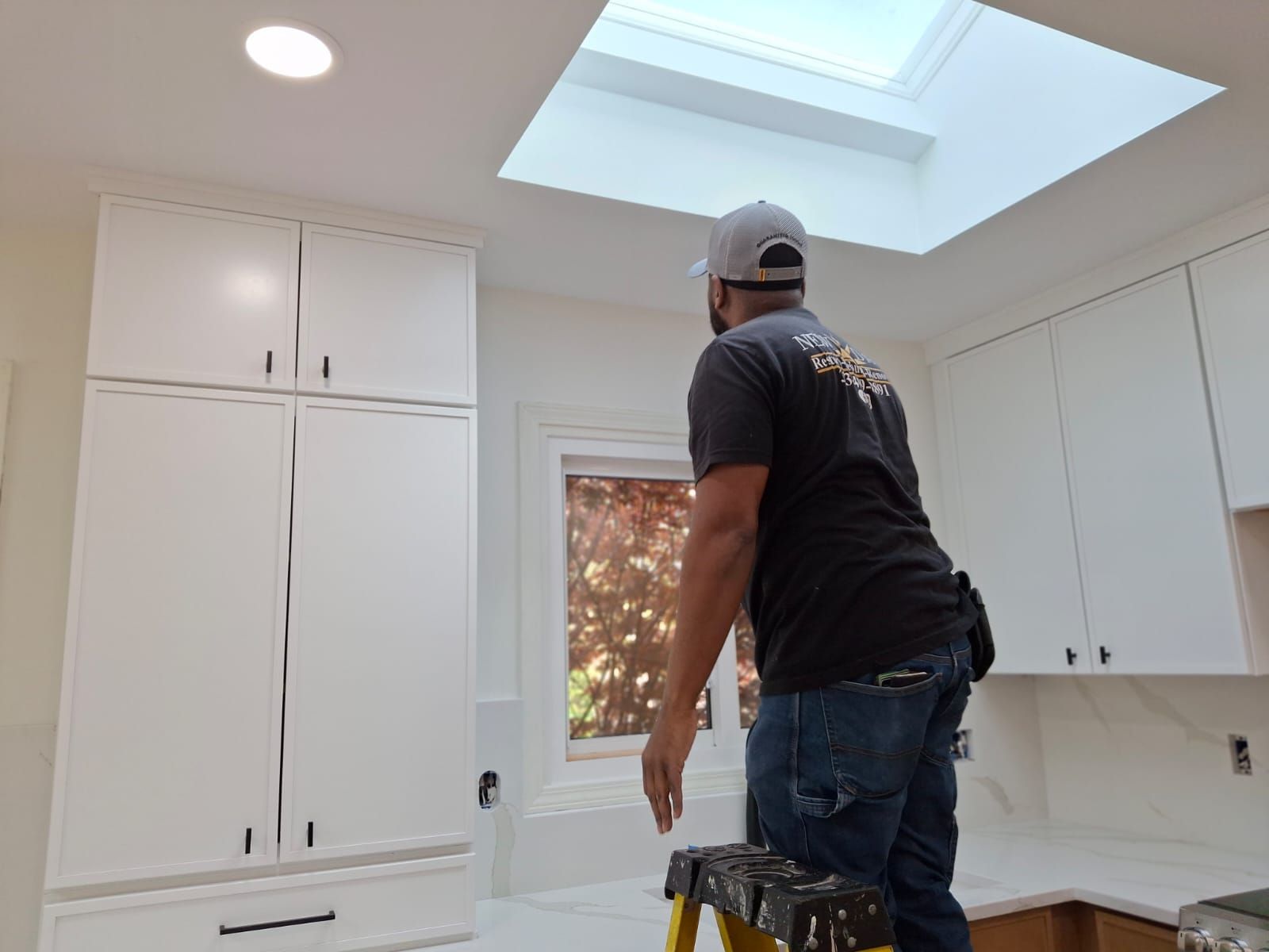 A man is holding a light bulb in his hand while working on a ceiling.