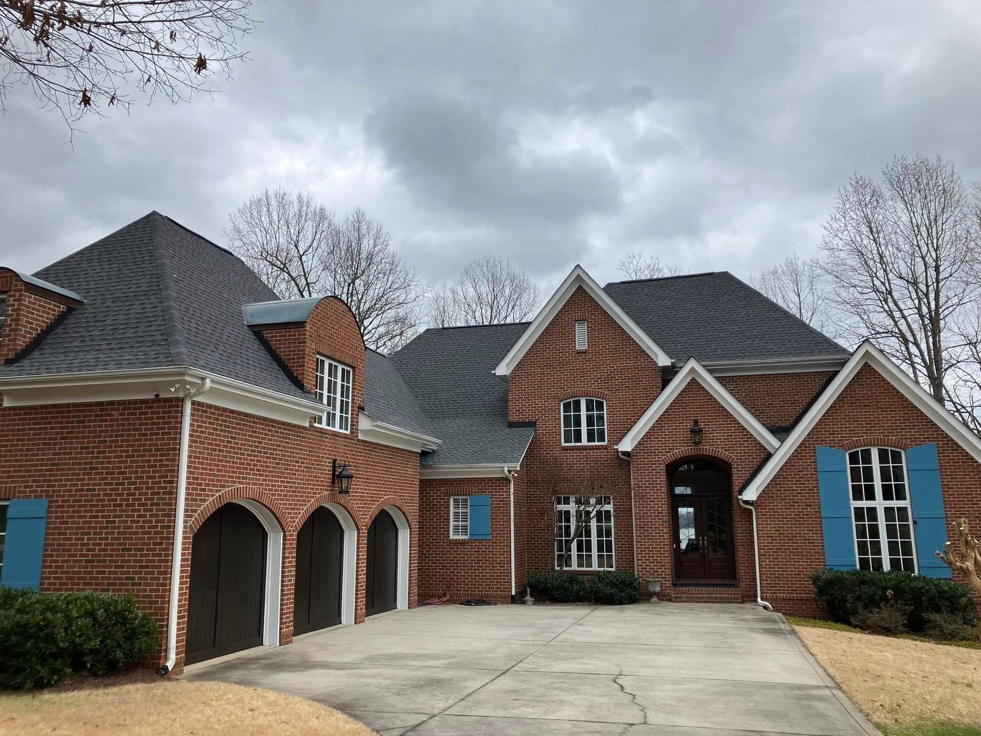 A large brick house with a gray roof and blue shutters.