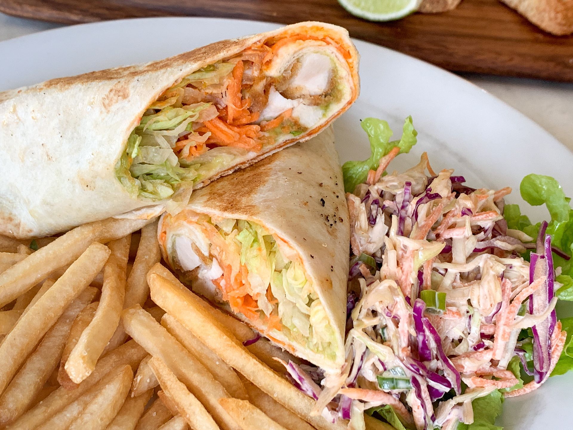Wrap Sandwich, Fries, and Coleslaw on a Plate. The Wrap is Cut in Half — Lazy Paul's Cafe 'n Smokehouse In Wauchope, NSW