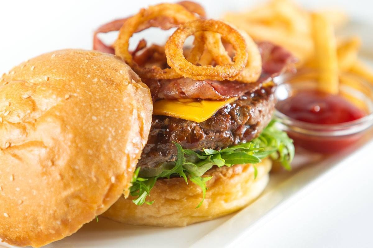Burger With Onion Rings, Bacon, Cheese, Lettuce, and Fries — Lazy Paul's Cafe 'n Smokehouse In Wauchope, NSW