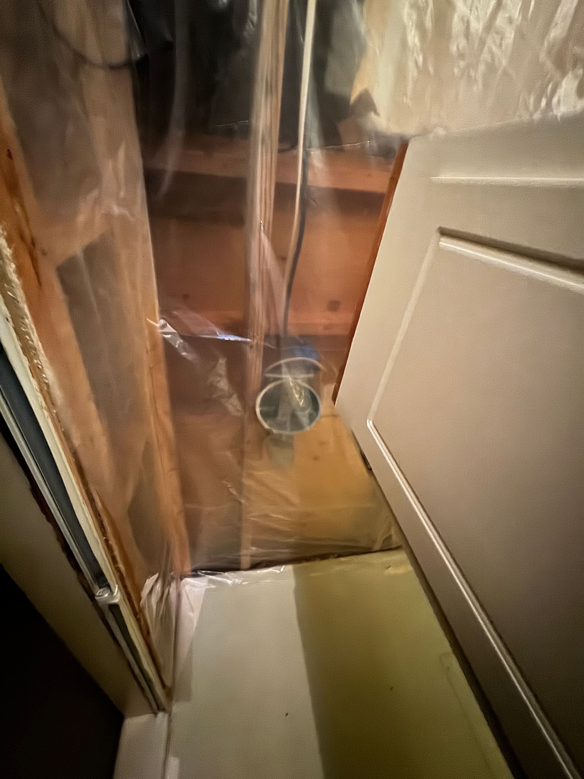View of exposed ceiling with ductwork and a partially visible white door.