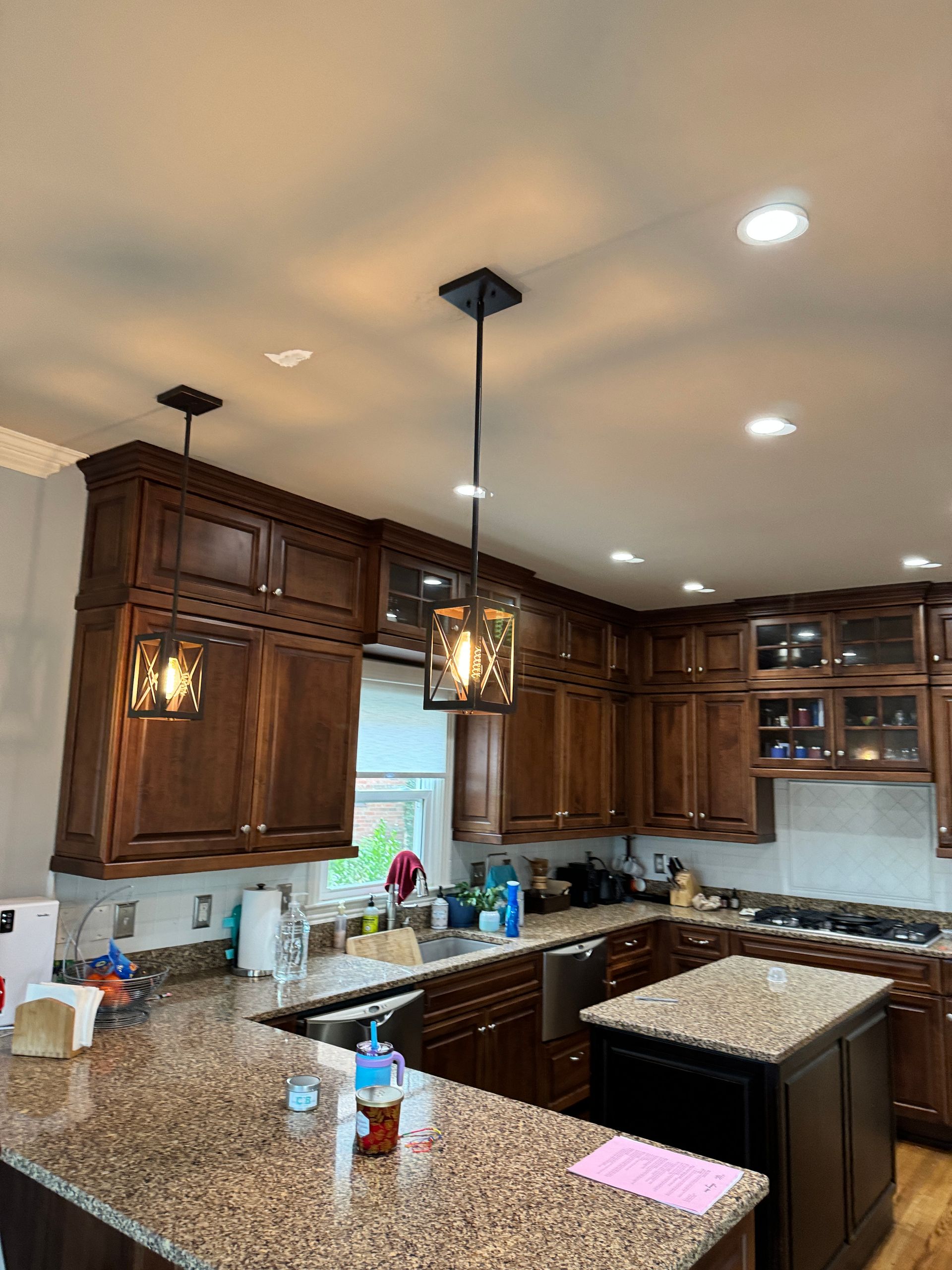 Kitchen with dark brown cabinets, granite countertops, and pendant lights.