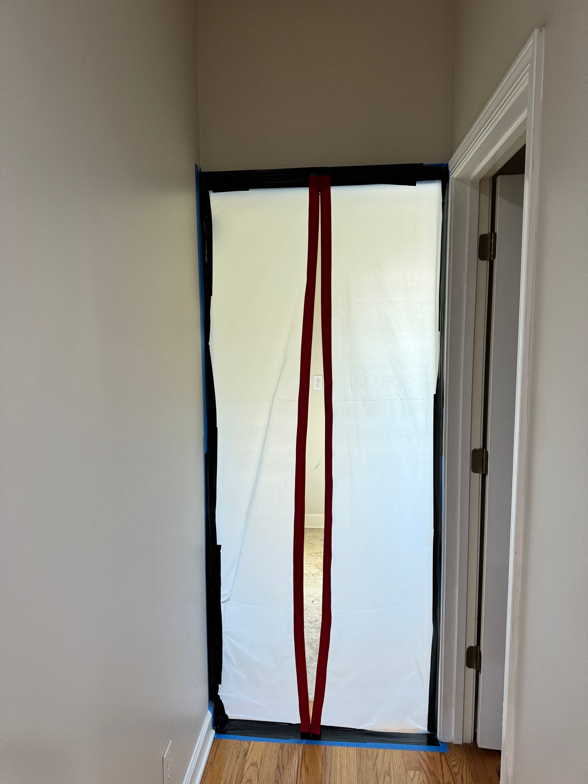 White sheet covering a doorway, outlined in black tape with a red vertical line.